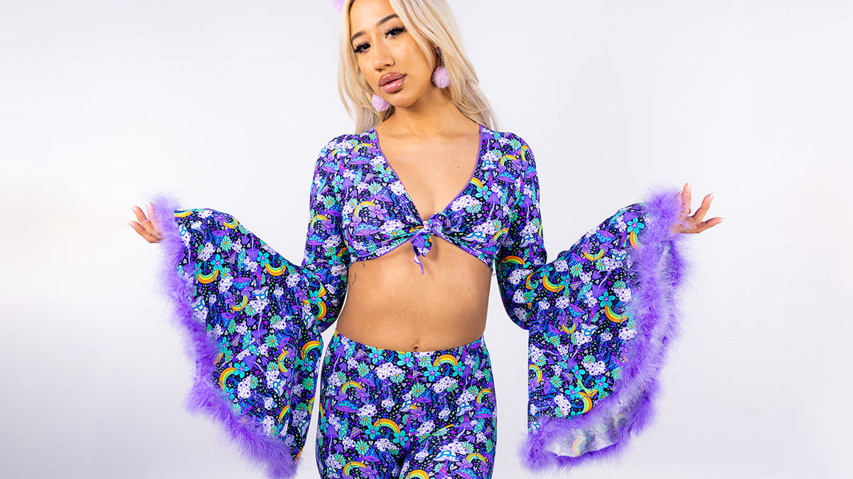 Model wearing a matching purple floral rave set with bell sleeves and flared trousers