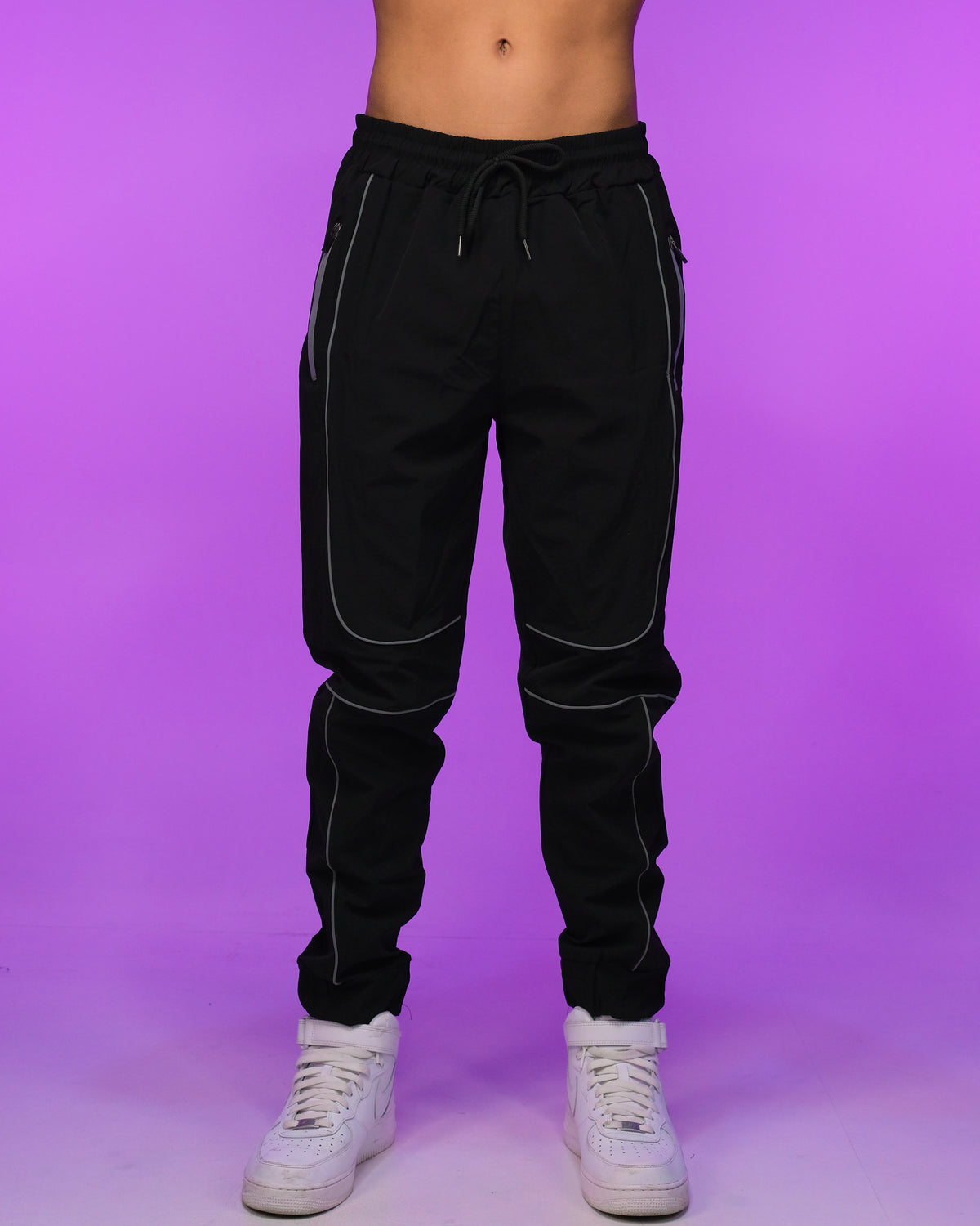 Black joggers with reflective piping accents, drawstring waist and tapered ankle cuffs