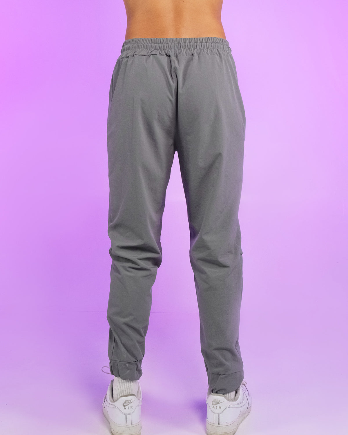 Gray reflective joggers from behind, elastic waistband and tapered ankle cuffs.