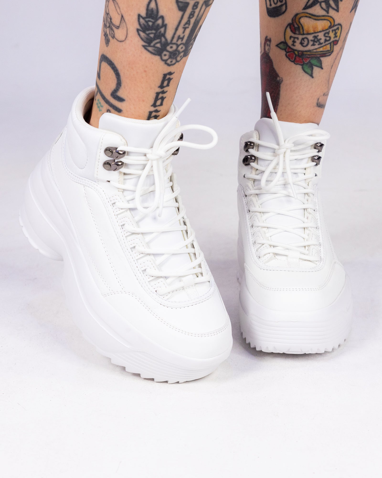 White lace-up hi-top sneakers with textured side panels and high platform sole