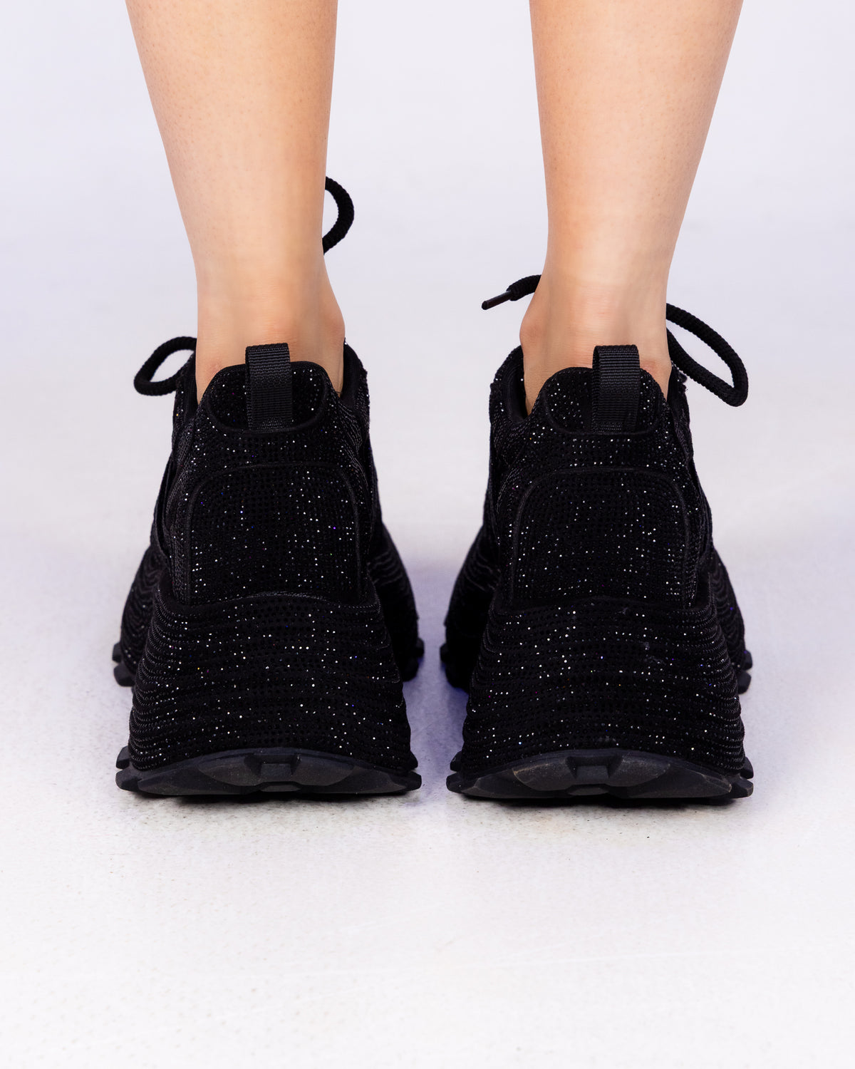 Black Crystal rhinestone wedge sneakers, all-black sparkle, back view on feet