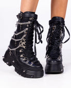 Black Holy Chains Edge mid-calf combat boots with silver chains, cross charms and lace-up front, front view