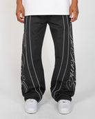 Black Monogram Men's Pants, black wide-leg with silver script monogram, front view on model