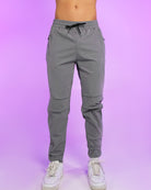 Gray reflective joggers with elastic waistband, black drawstring, tapered legs.