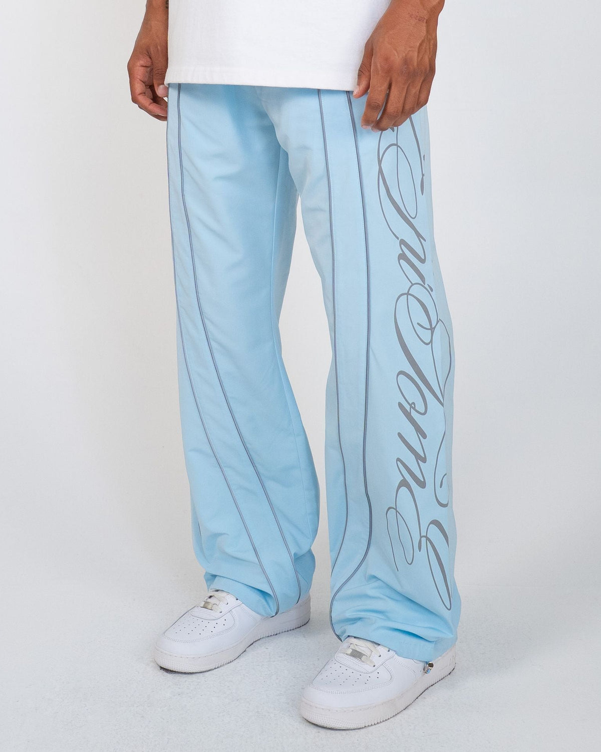 Sky Blue Monogram Men's Pants, light blue wide-leg with gray script monogram and piping, angled view on model