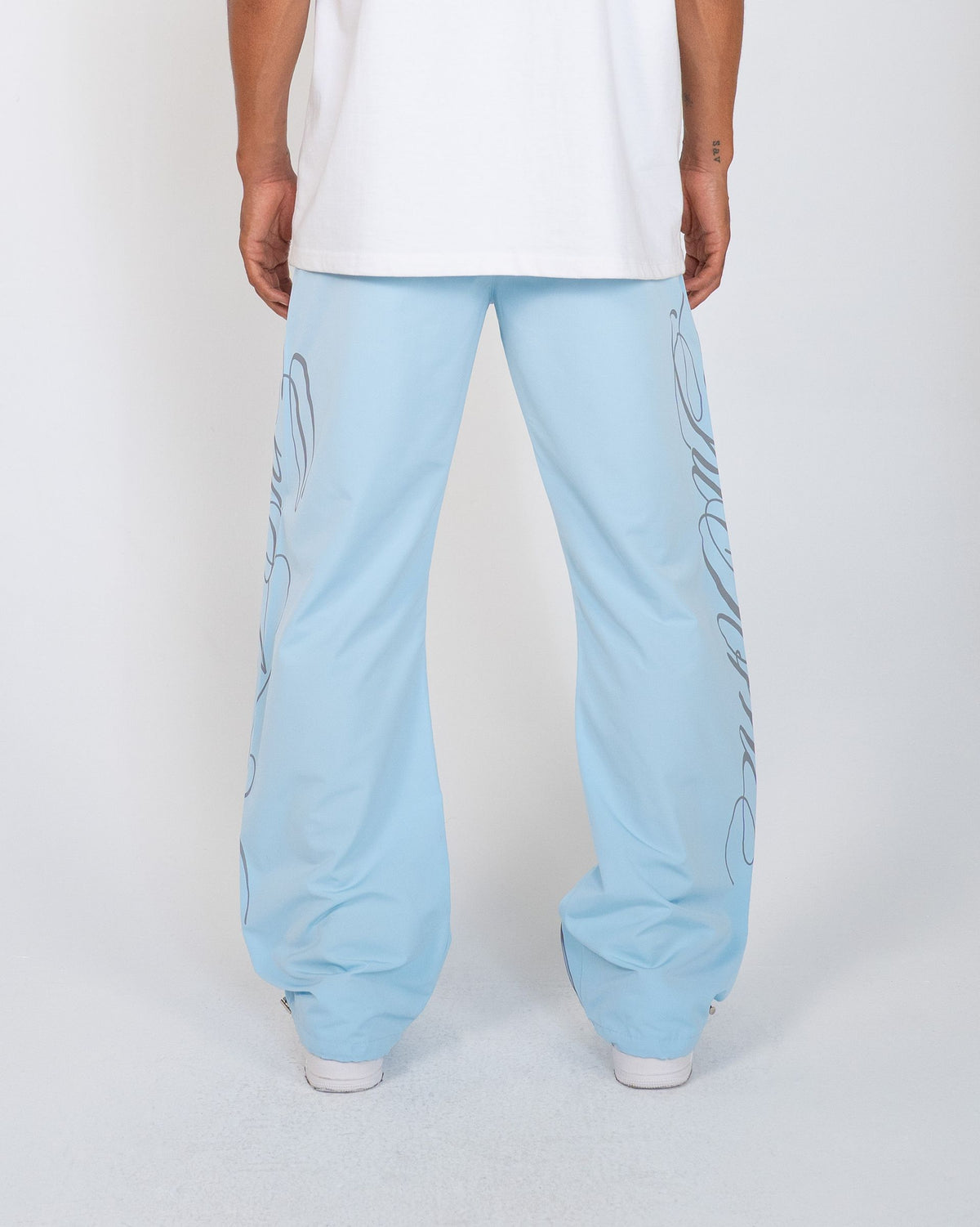 Sky Blue Monogram Men's Pants, light blue wide-leg with script monogram, back view on model